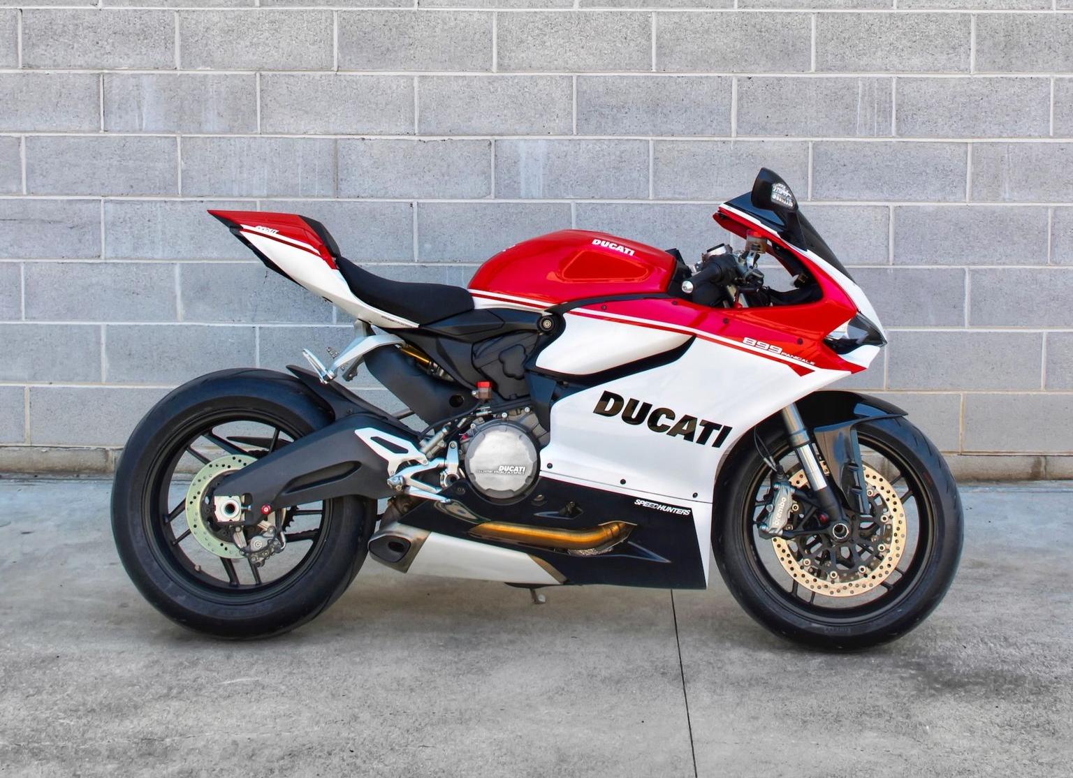 red and black sports bike parked beside white brick wall